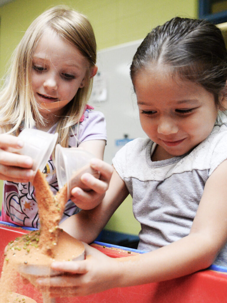 Check out these preschoolers at Spark! Discovery Preschool playing with cups and sand.