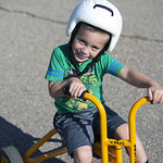 Child rides a tricycle while wearing a helmet.