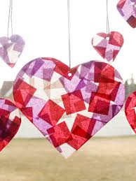 Colorful heart-shaped decorations made of translucent tissue paper, hanging against a light background.